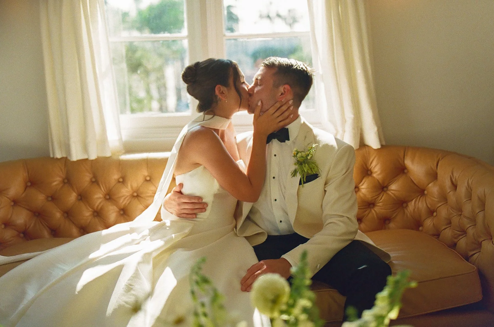 A bride and groom kissing on a couch
