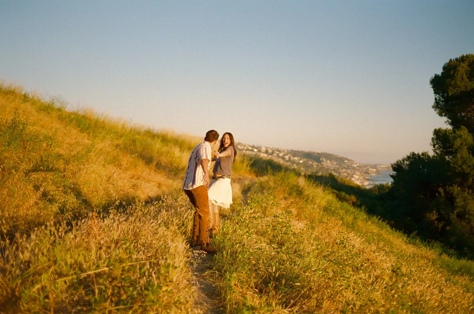 A couple walking through a field overlooking Laguna Beach