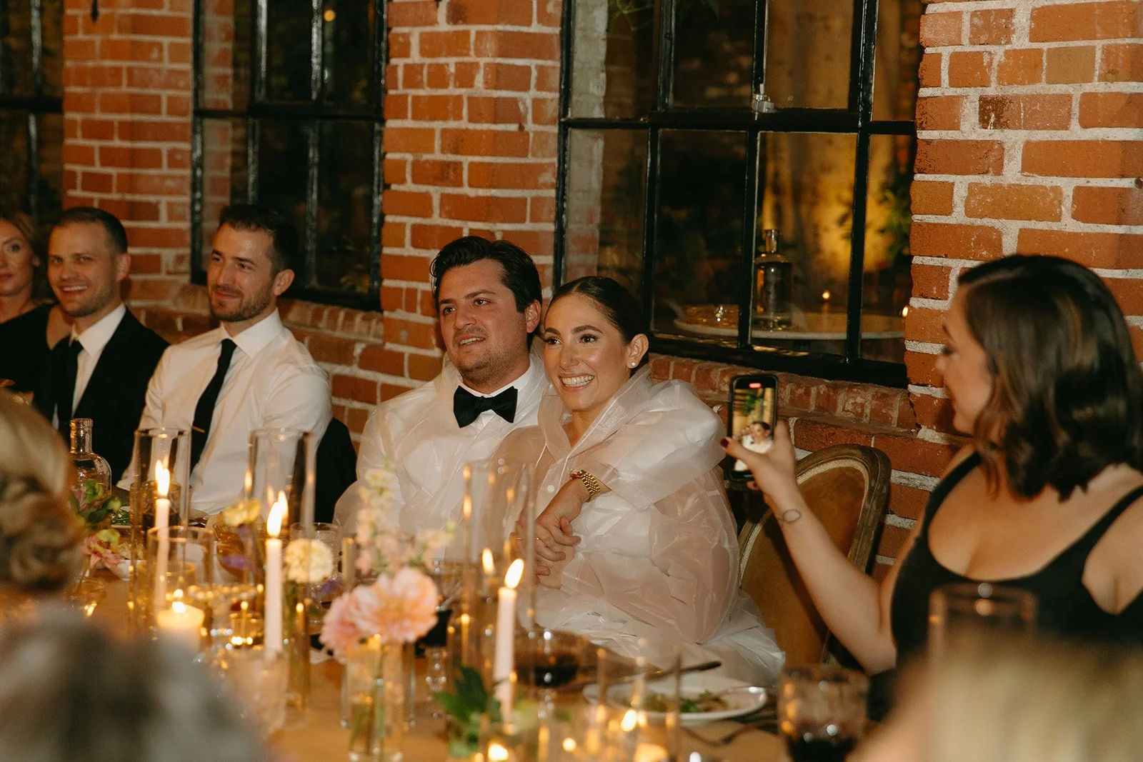 The bride and groom smiling and listening to their speeches.