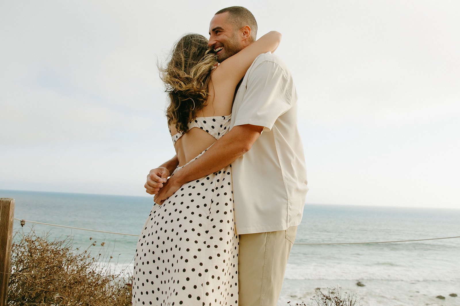 A couple hugging while taking beach engagement photos