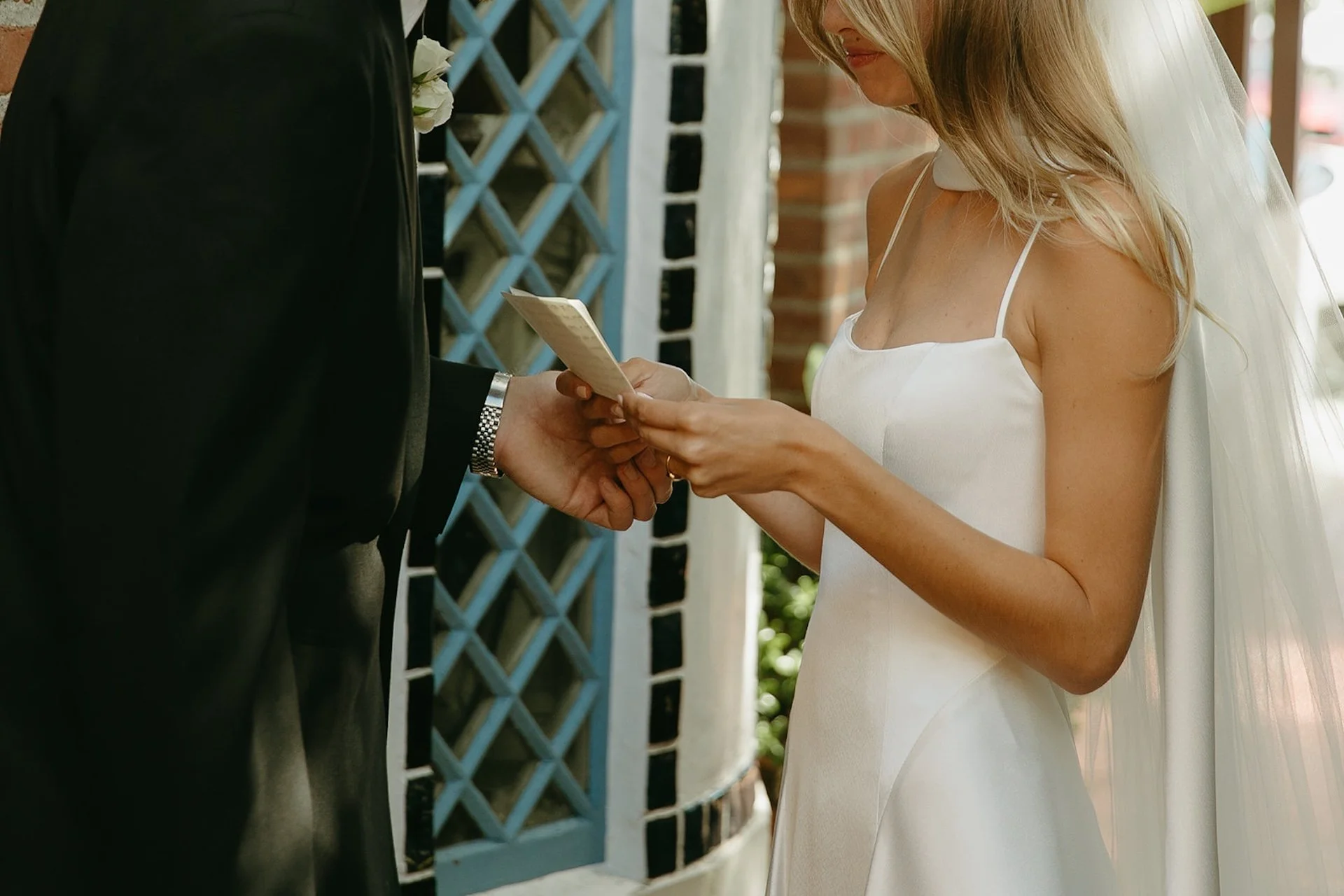 Bride holding and reading her handwritten vows during an intimate Laguna Beach wedding moment outside the church.