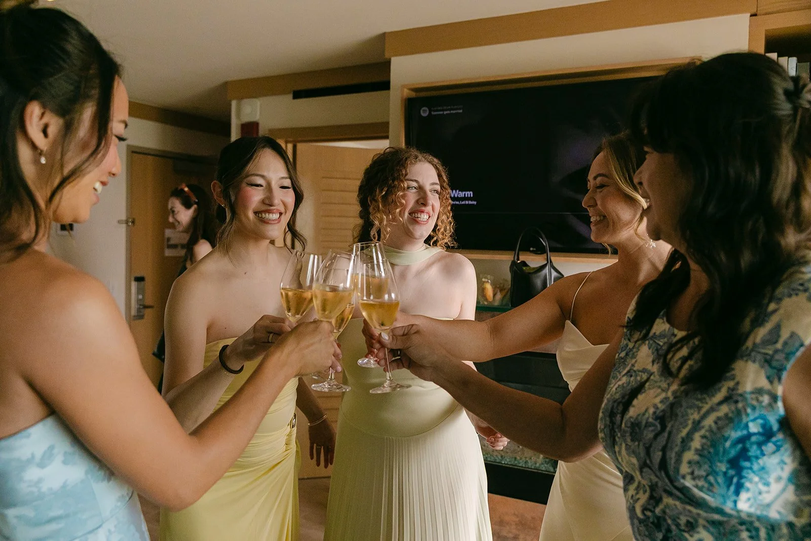 A bride clinking wine glasses with her bridesmaids