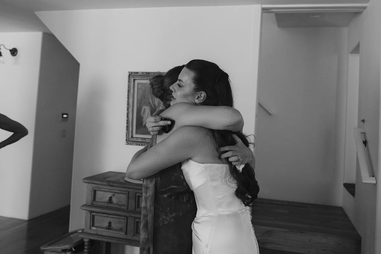 A bride hugging a bridesmaid in a candid wedding photo