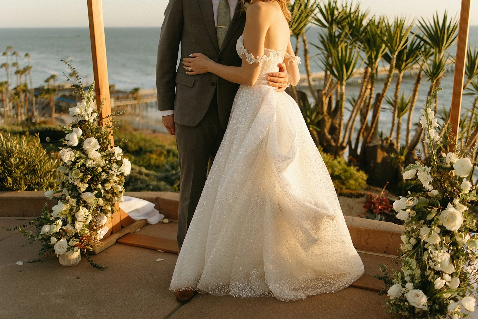 Bride and groom standing together at their oceanfront ceremony at one of the most iconic San Clemente Wedding Venues, framed by florals and coastal views.