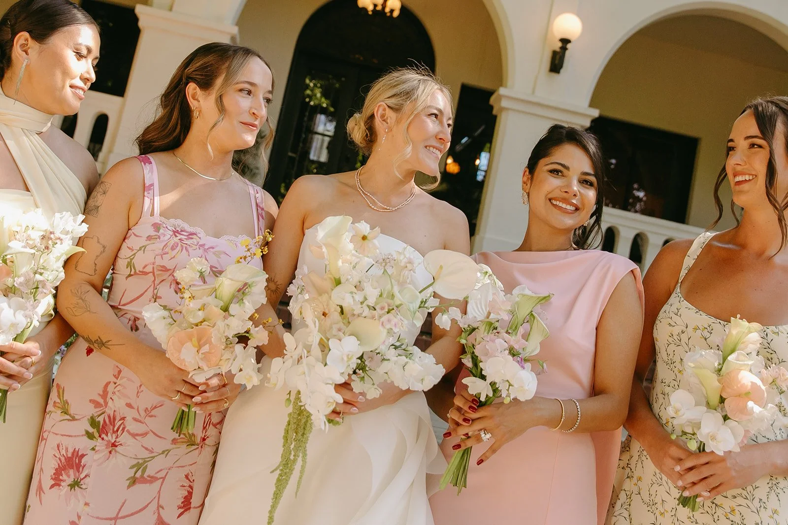 Bridesmaids in pink and yellow dresses posing for wedding photos at an estate wedding venue