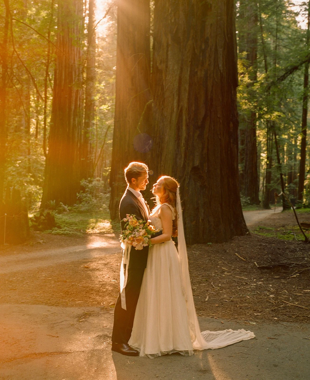 A bride and groom taking film wedding photos in the forest at their garden wedding