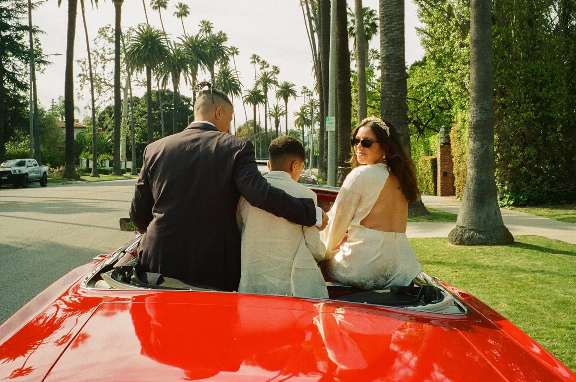 Newlyweds and their son sitting in the backseat of a red convertable after their Beverly Hills Courthouse Elopement