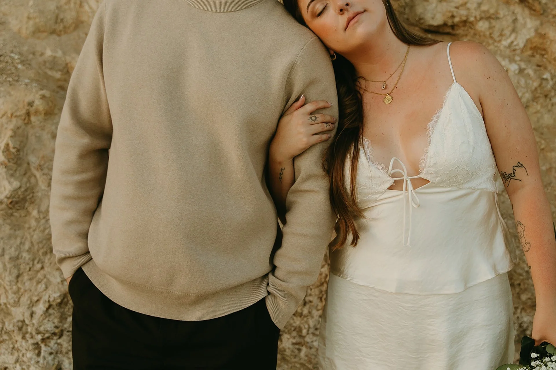 Beach Engagement Photo Ideas of a close-up portrait of a couple leaning into each other with rocky cliffs in the background.