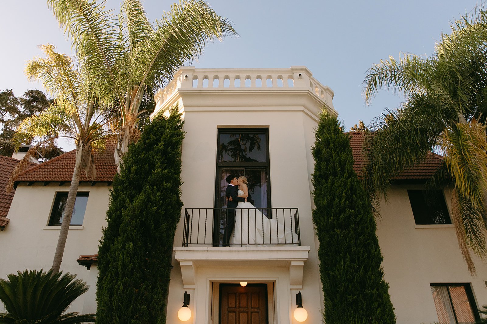 A bride and groom on the balcony of their estate wedding venue
