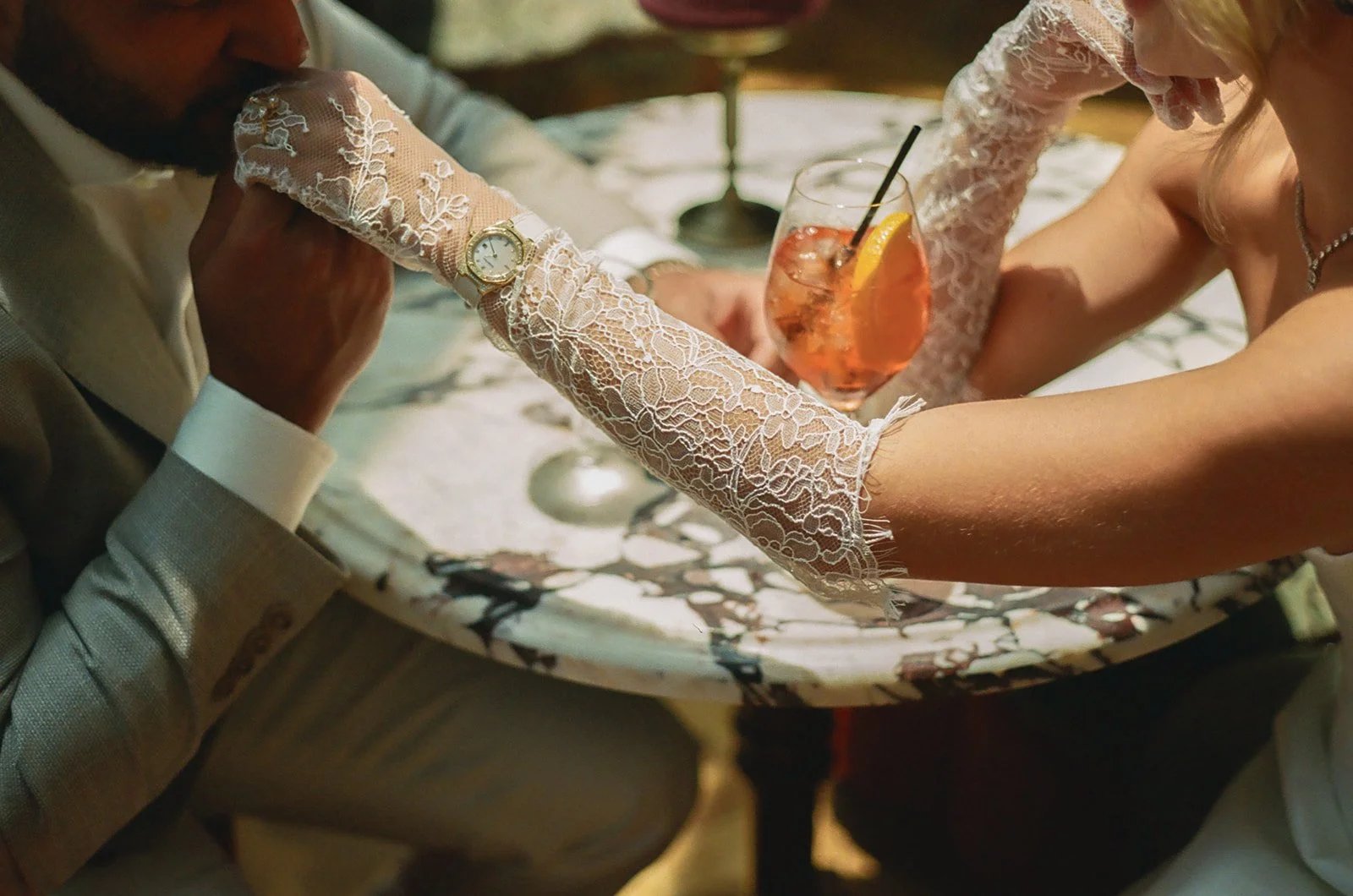 A man kissing his fiancees hand over cocktails