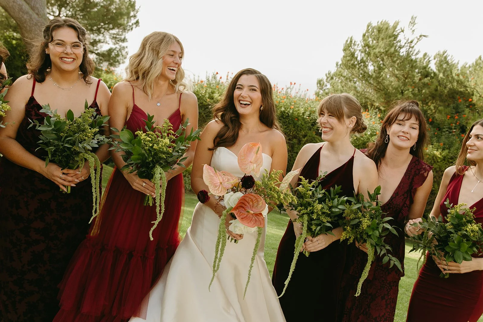 Bride laughing with her bridesmaids as they walk together holding bouquets, photographed by a Los Angeles wedding photographer.