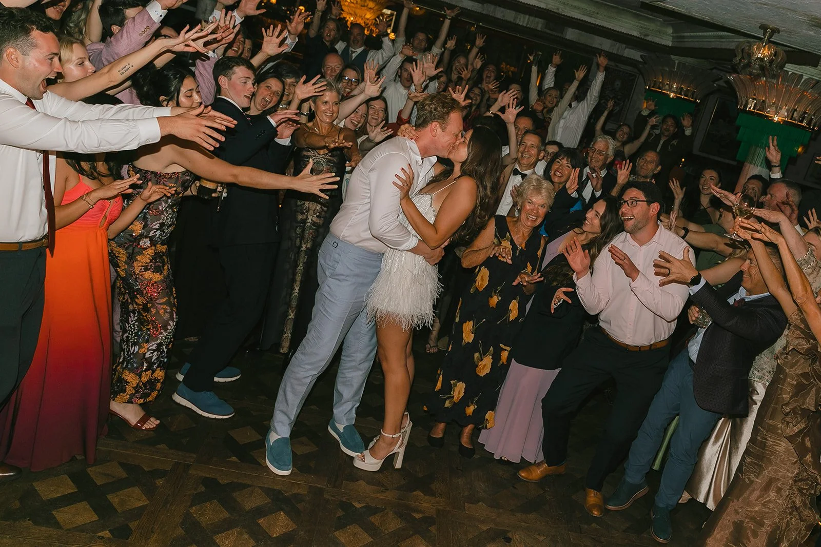 A bride and groom kissing in front of wedding guests