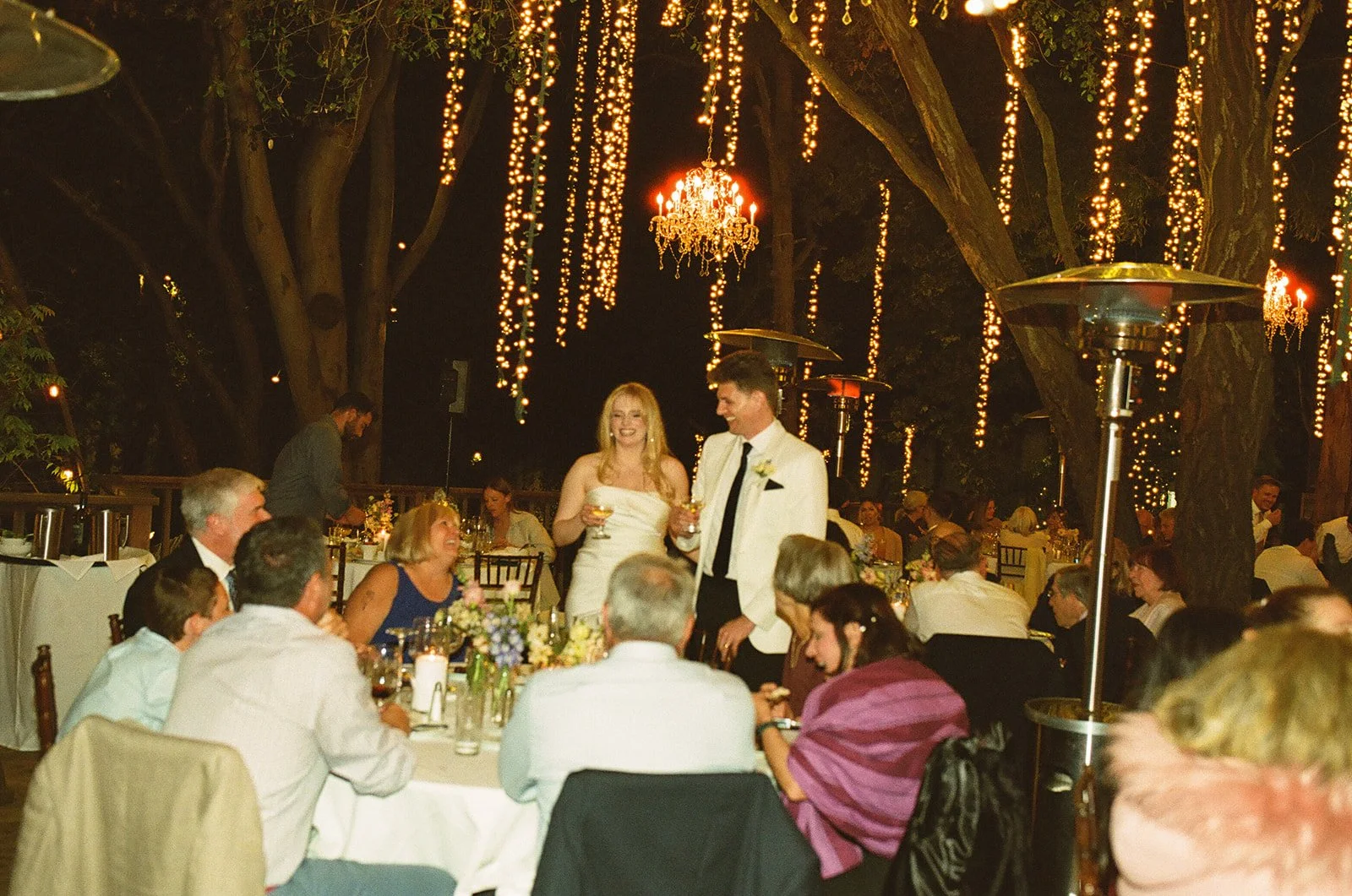 A candid wedding photo of a couple talking to guests at their reception