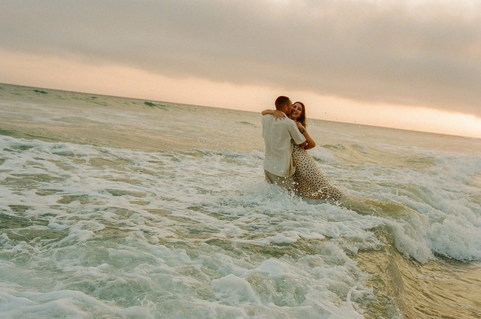 A couple in the ocean during their engagement photoshoot