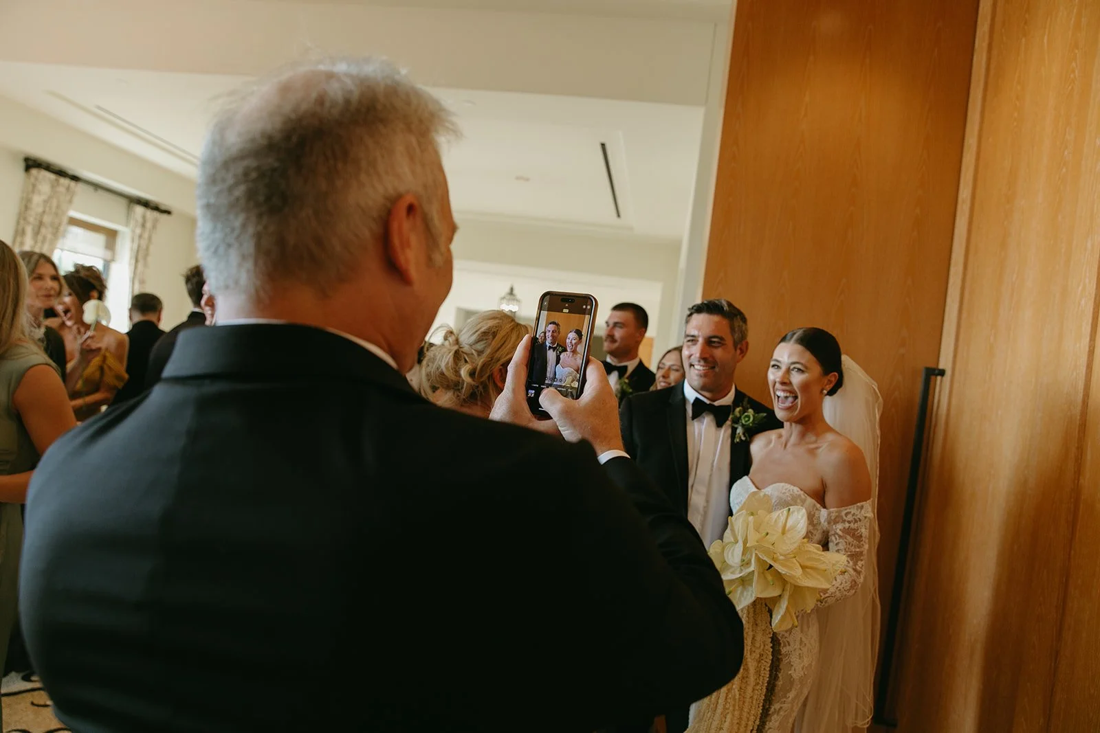 A man taking pictures of a bride and groom on his phone