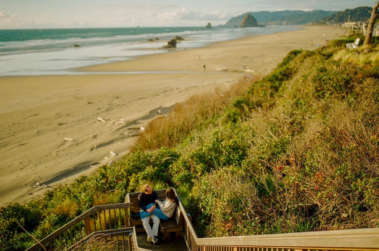 A couple sitting on a dock during beach engagement photos