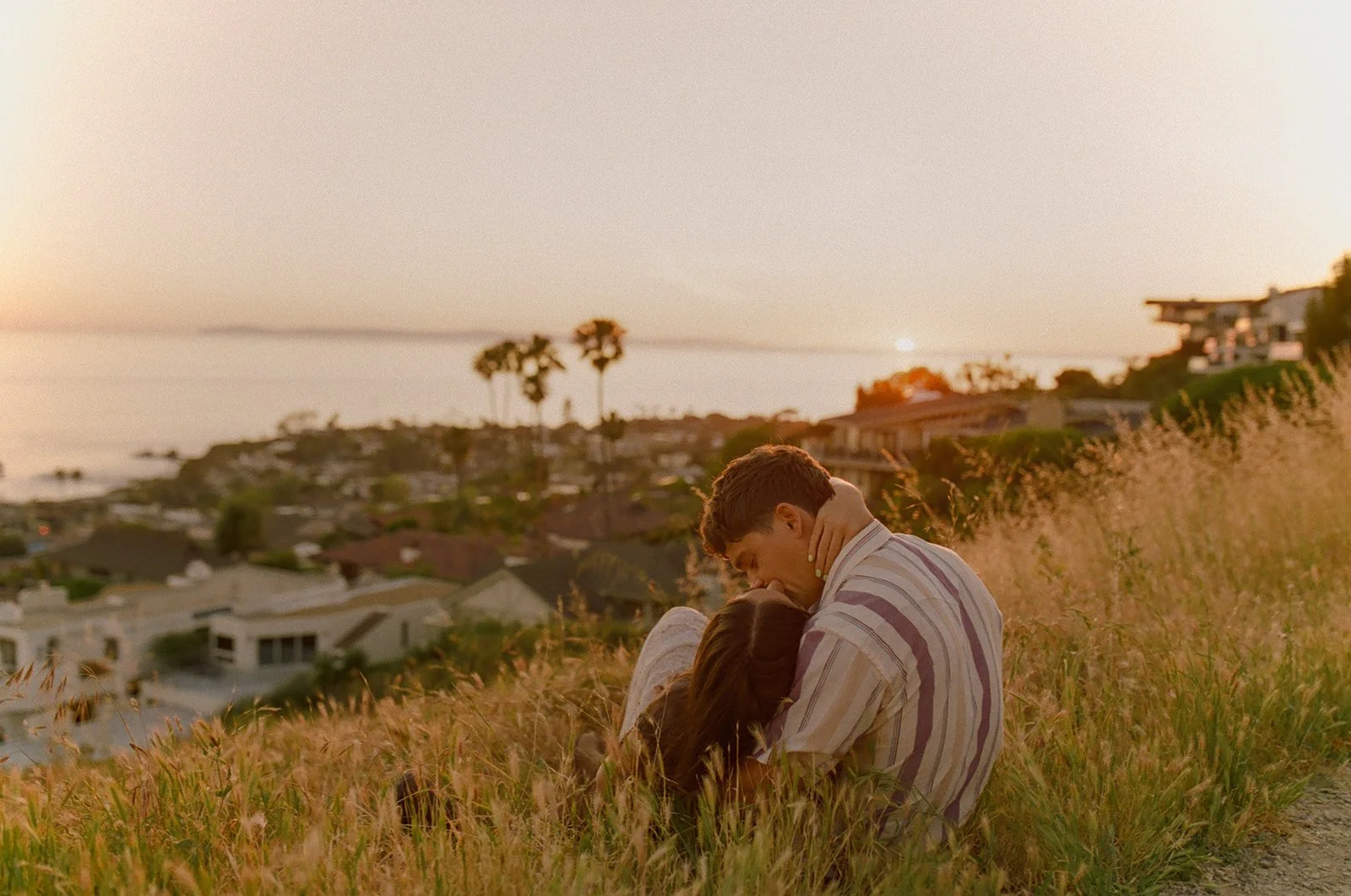 A couple kissing in a field during their film engagement photos