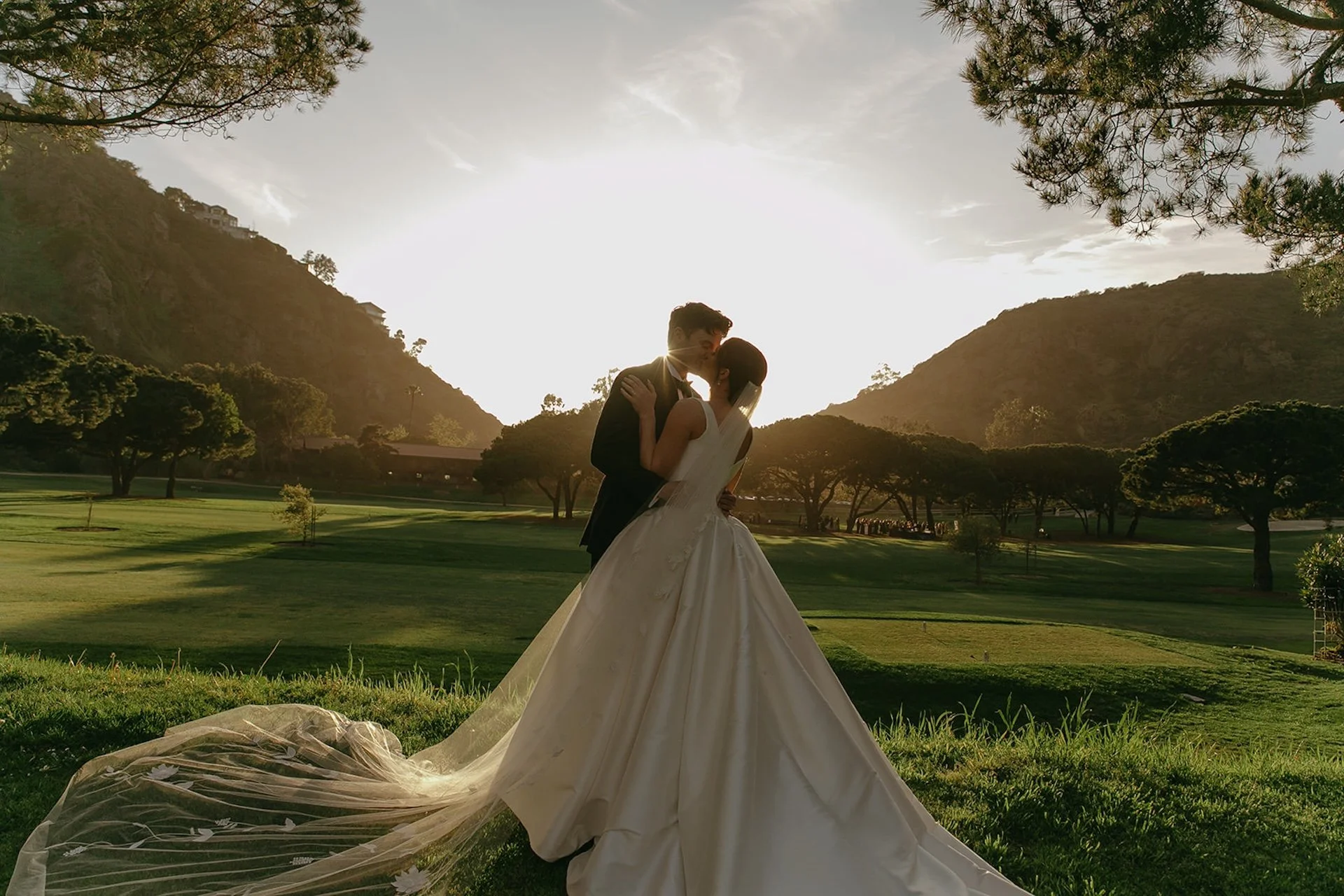 Romantic sunset kiss with veil trailing across the grass at The Ranch at Laguna Beach wedding golf course.
