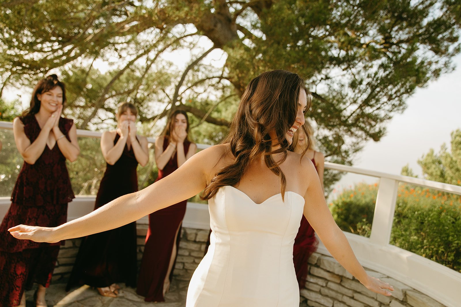Bride spinning playfully in her dress as her bridesmaids react behind her at a Historic Wedding Venue.