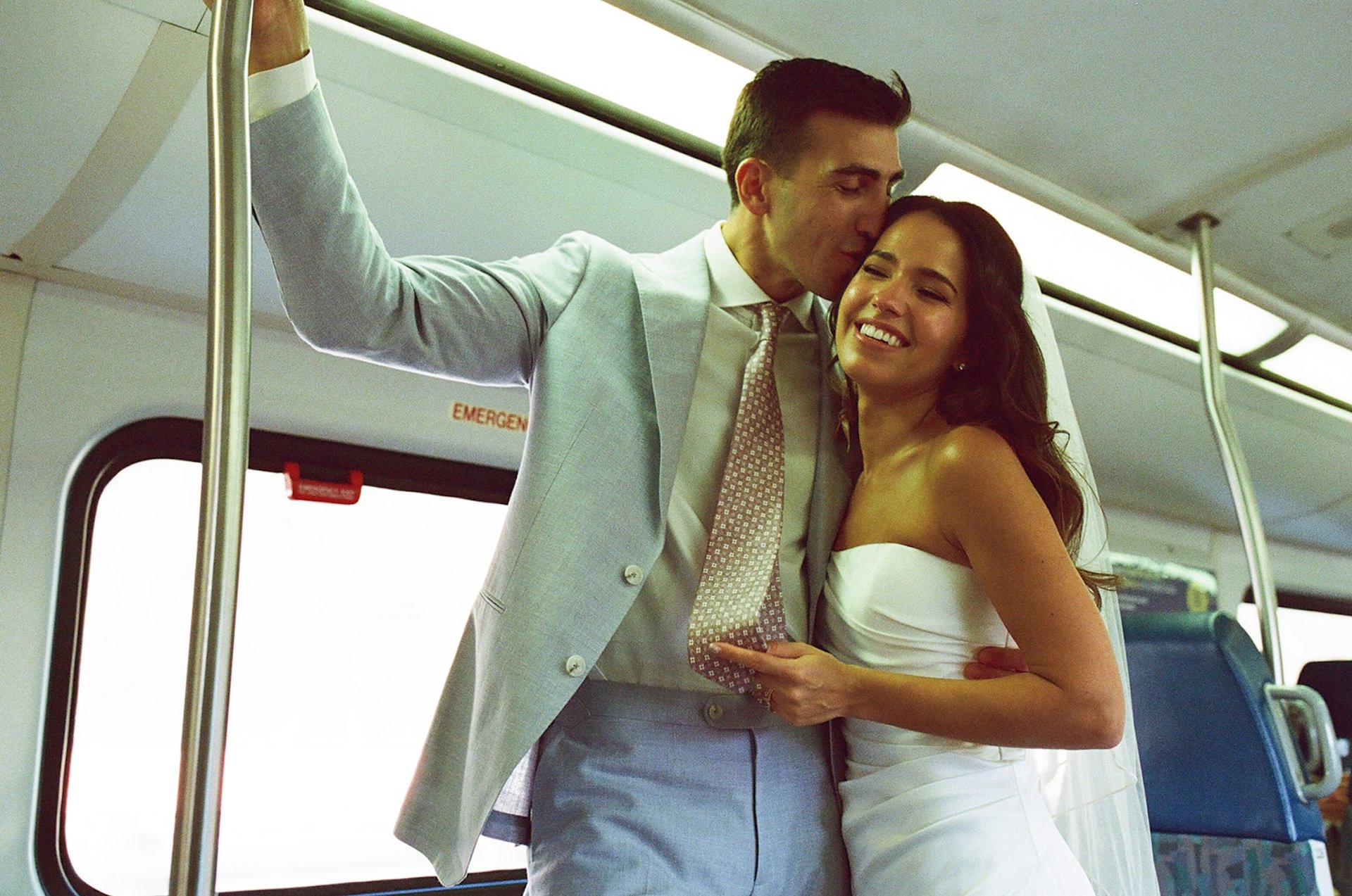 The groom kisses the bride’s temple while they stand on the train at a San Juan Capistrano Wedding Venue.