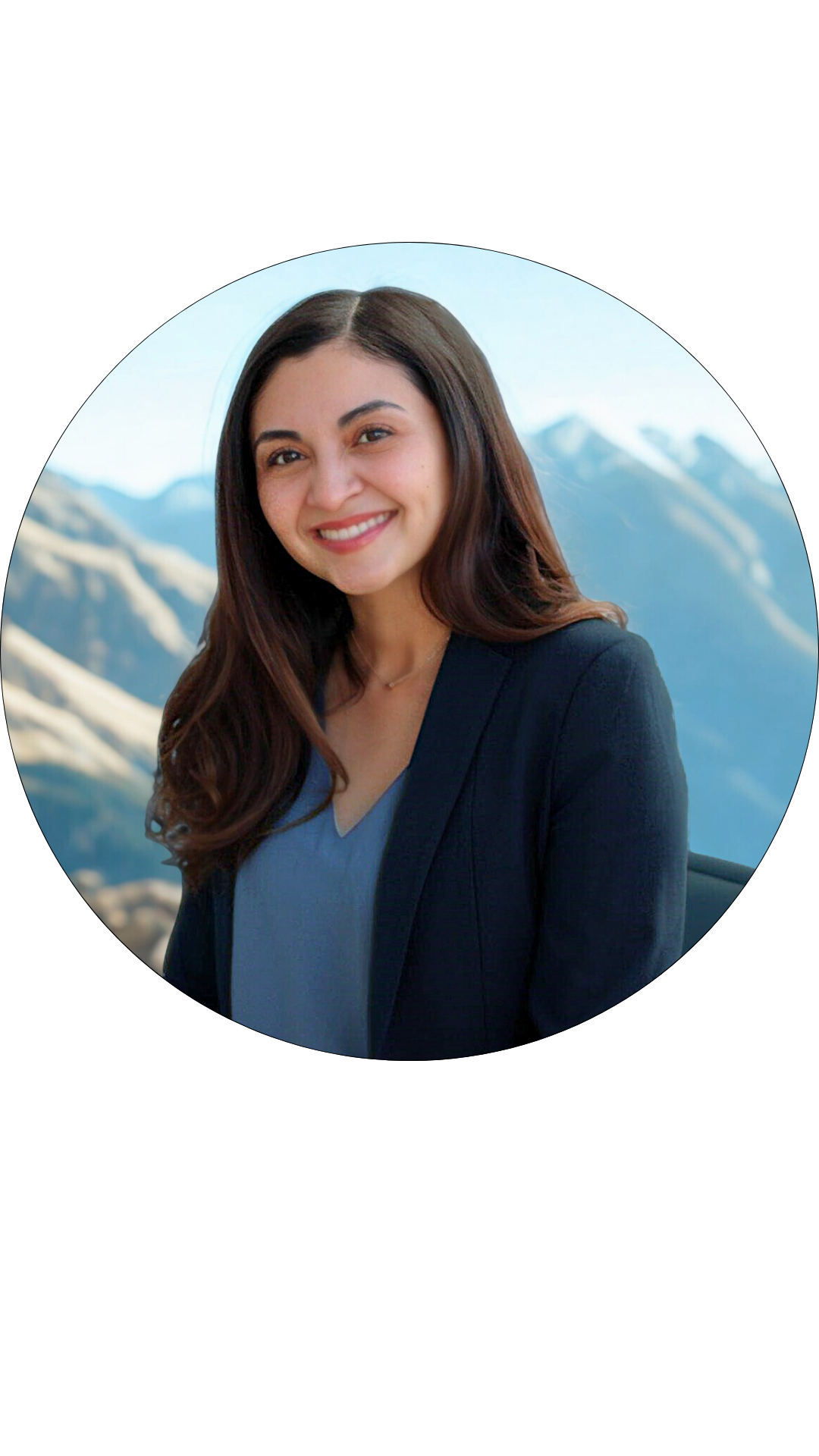 A woman with long brown hair and a black blazer smiling outdoors with mountain scenery in the background.