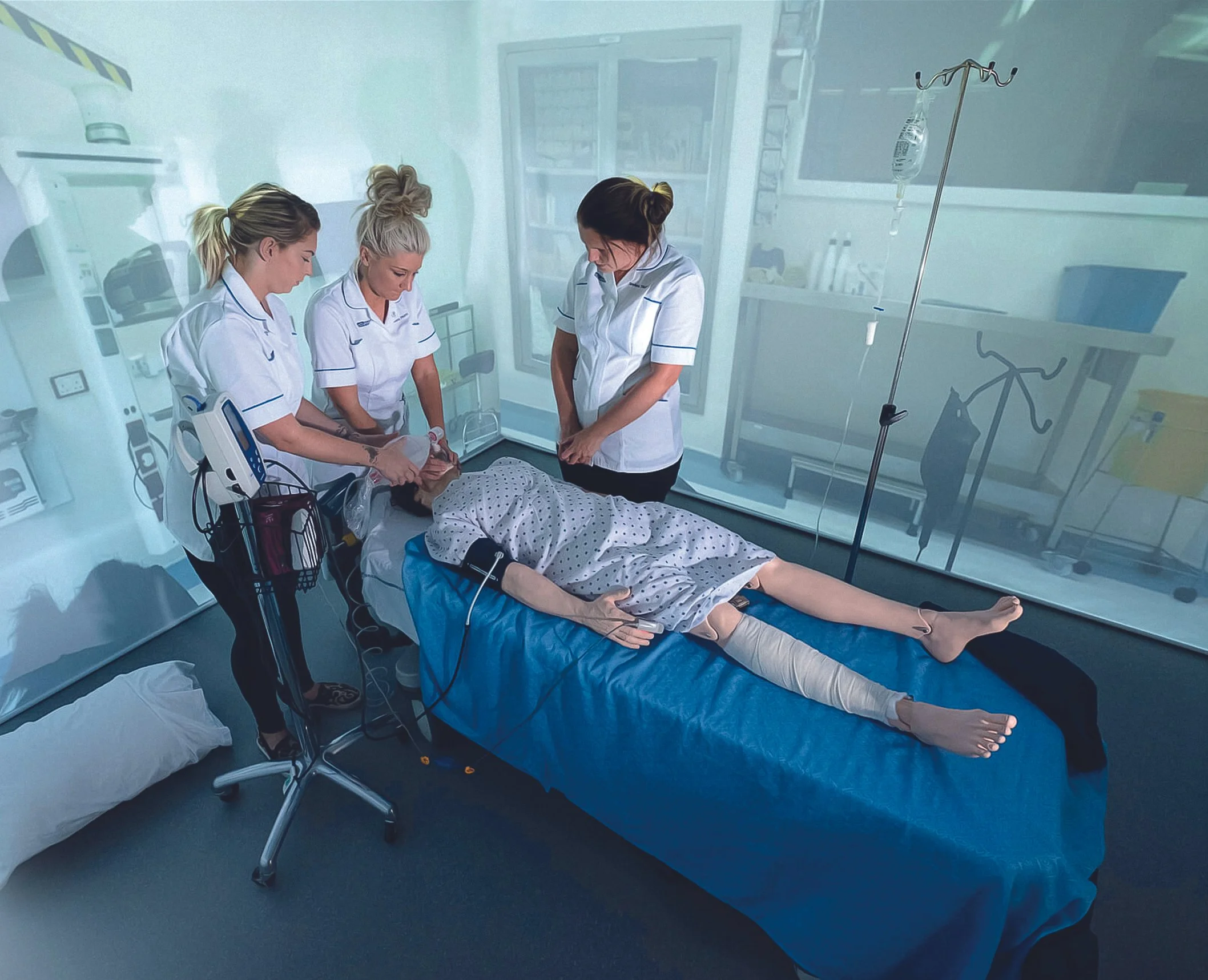 Nursing students practicing patient effective care with a medical manikin in a simulated hospital environment as part of vocational healthcare training.