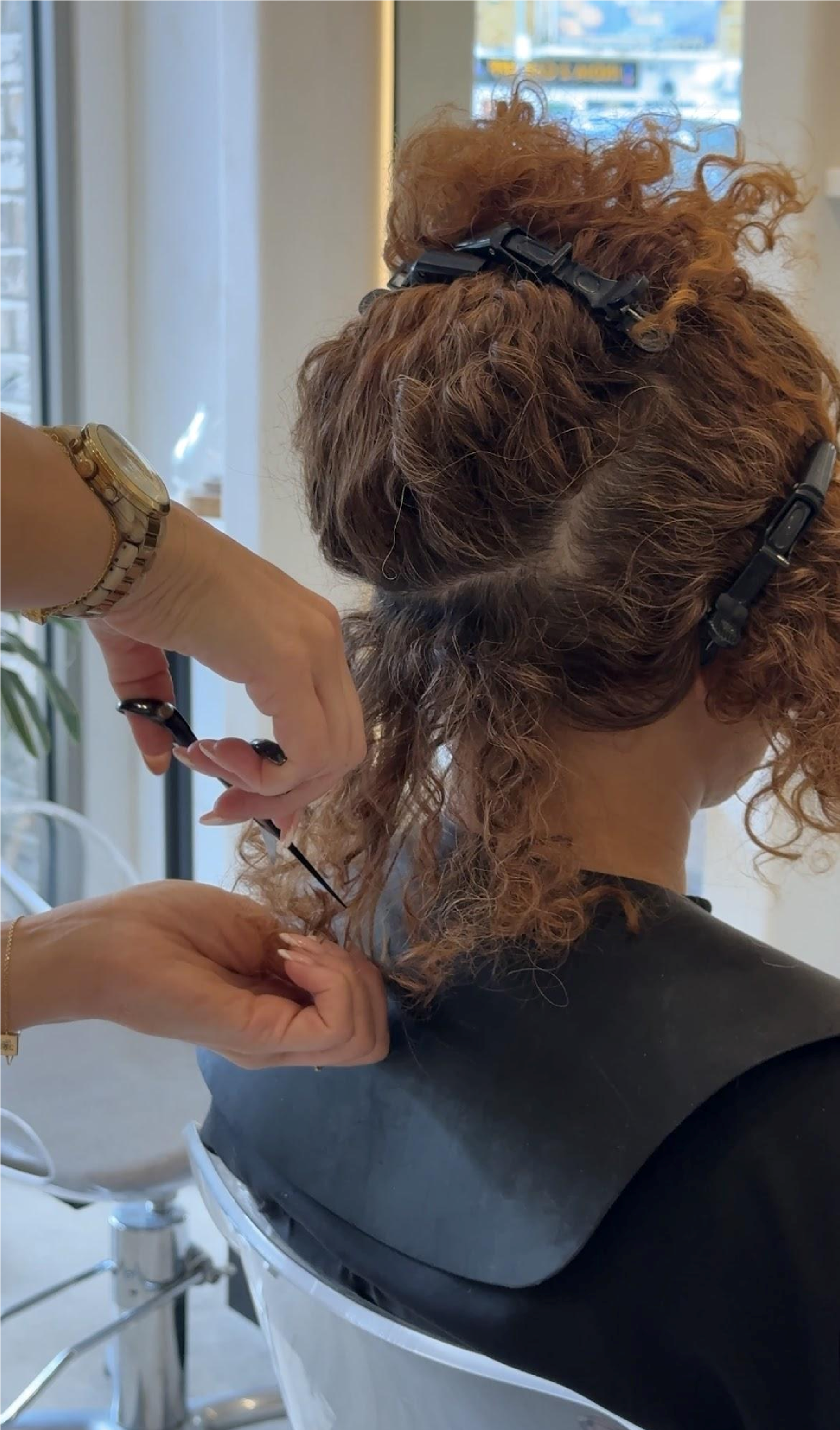 Stylist sectioning and cutting curly hair dry with clips at Thriv salon