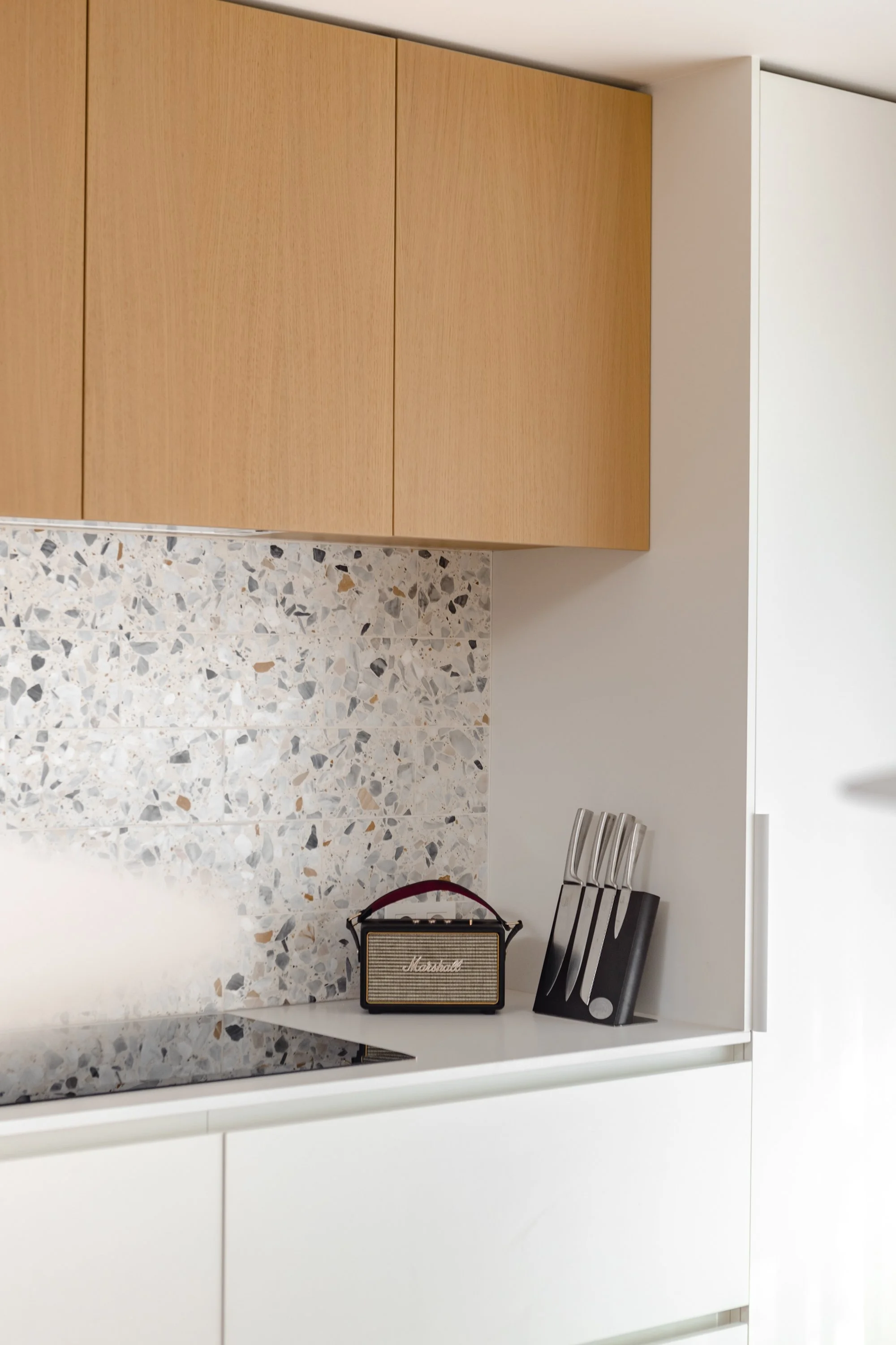 Moderne keuken met witte kasten, terrazzo aanrechtblad, houten kastdeuren, een Marshall versterker,  ingewerkte greeplijst