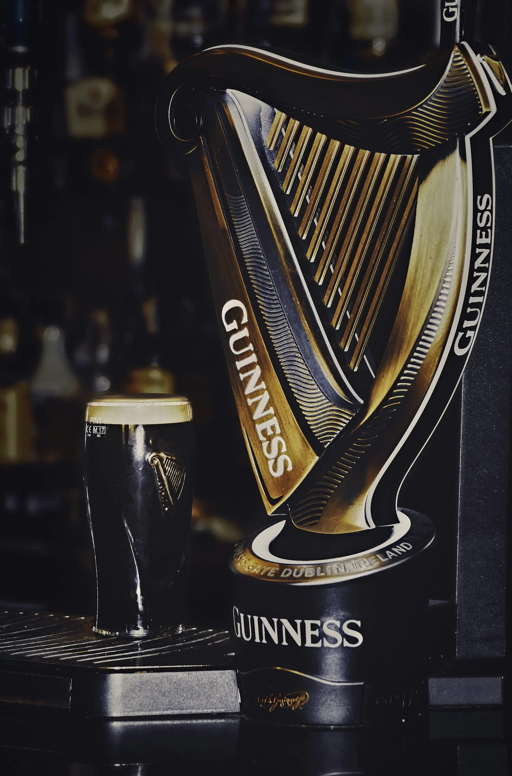 A pint of Guinness beer on a bar counter alongside a 3D Guinness harp display.