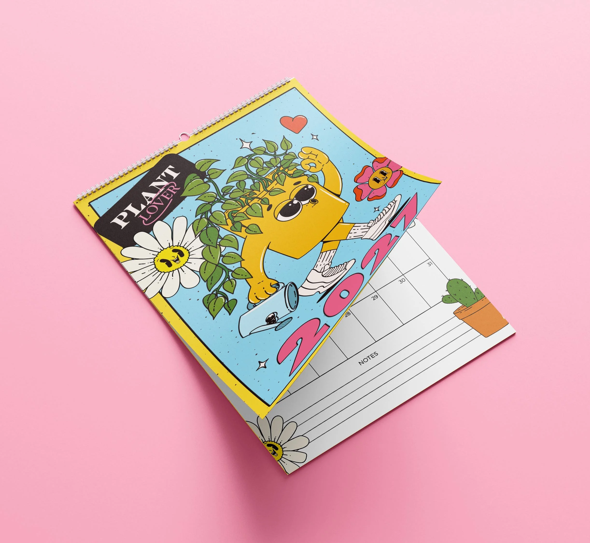 Sofe Store 2027 plant lover wall calendar lying at an angle with the cartoon plant cover lifted to reveal a monthly page with a potted cactus and Notes section