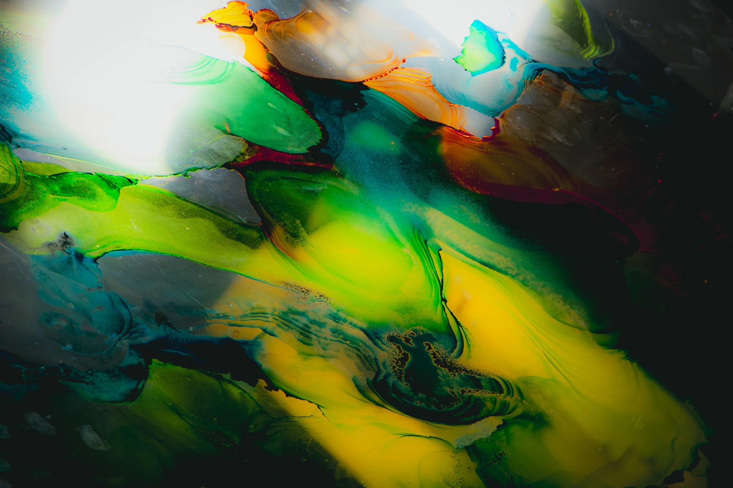 Abstract swirl of vibrant colors including green, yellow, orange, blue, black, and white created with fluid painting techniques.