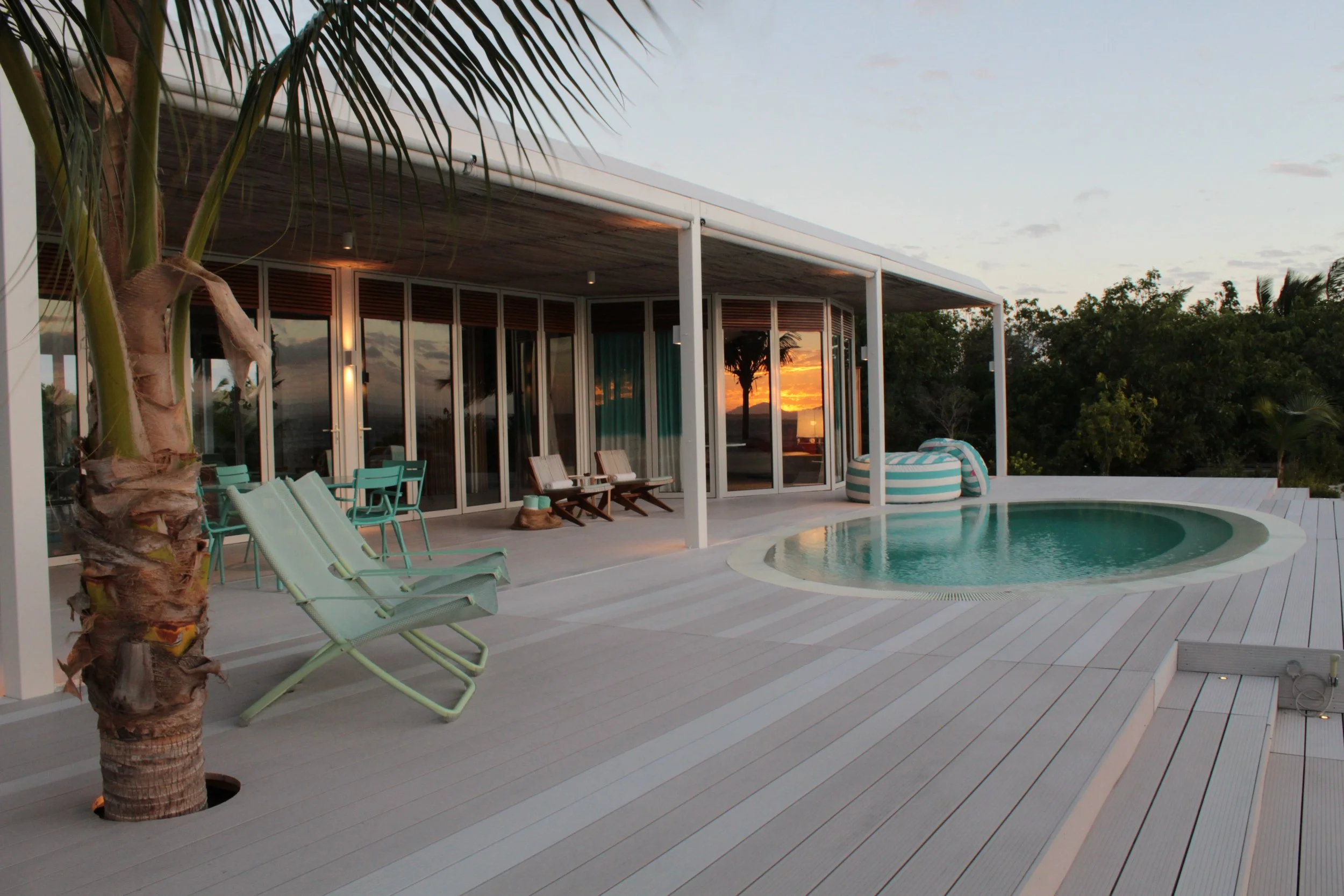 A Miavana villa's deck with a sunset reflected in the windows