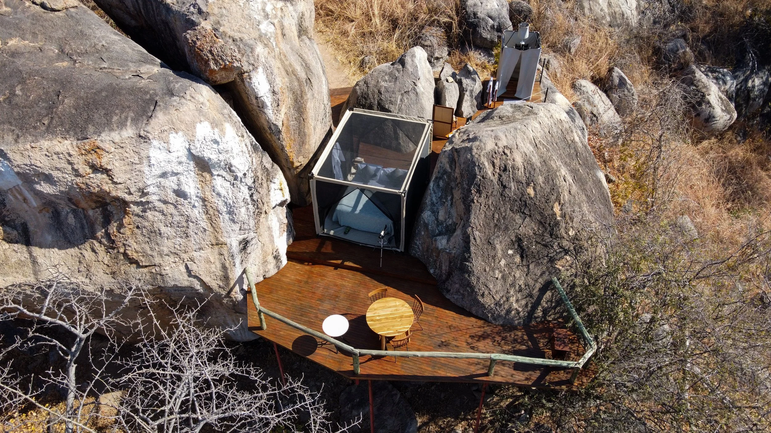 A bed, under mosquito nets nestled between huge rocks in Ruaha National Park