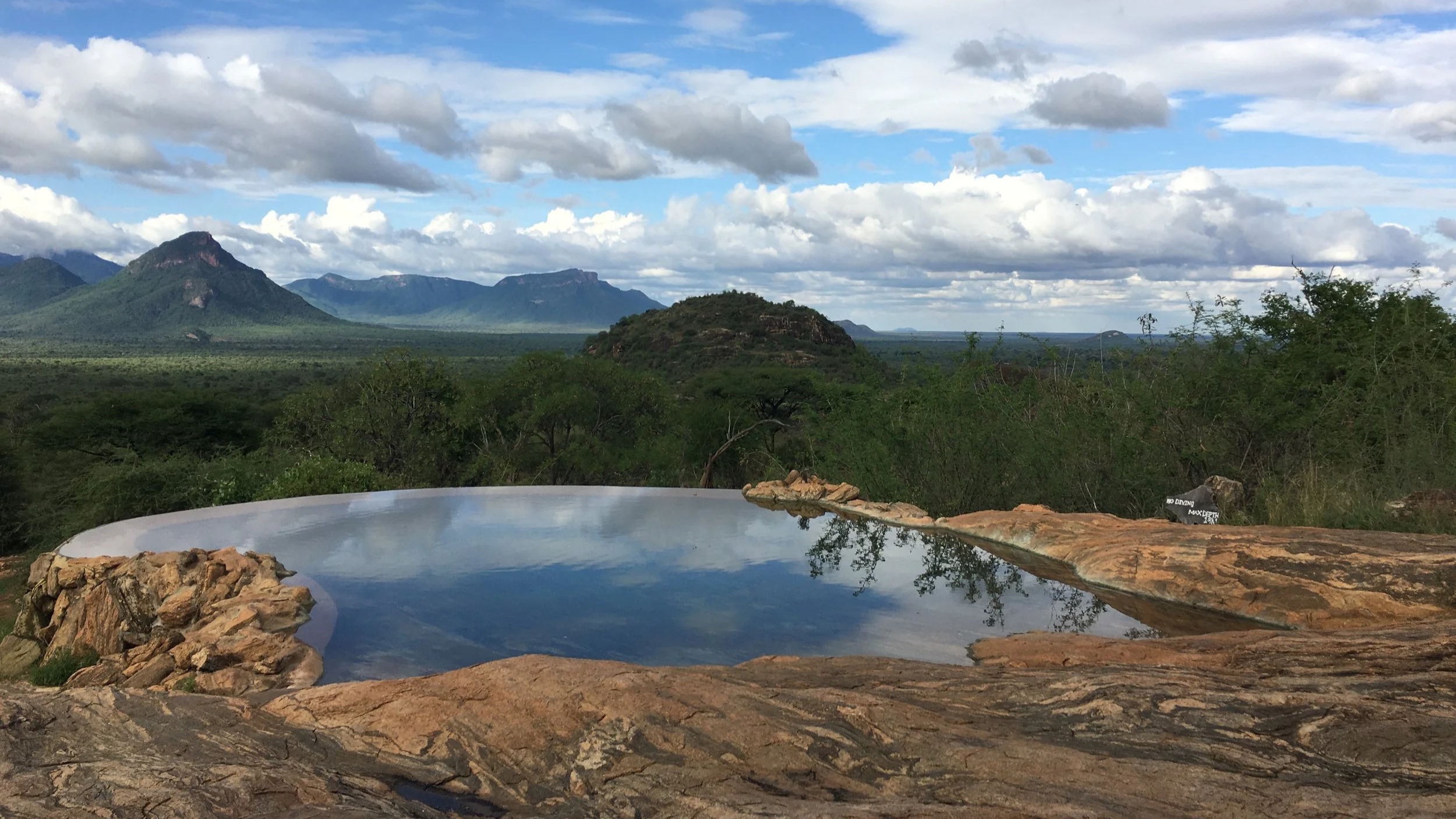 A swimming pool reflects the sky with mountains in the distance
