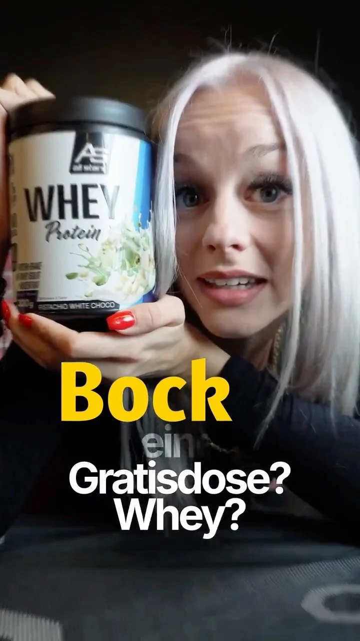 Junge Frau mit langem, hellem Haar hält eine Dose Proteinpulver in die Kamera, steht vor einer dunklen Hintergrund und spricht mit einer erstaunten Miene. Der Text auf dem Bild lautet: "Bock ein Gratisdose? Whey?"