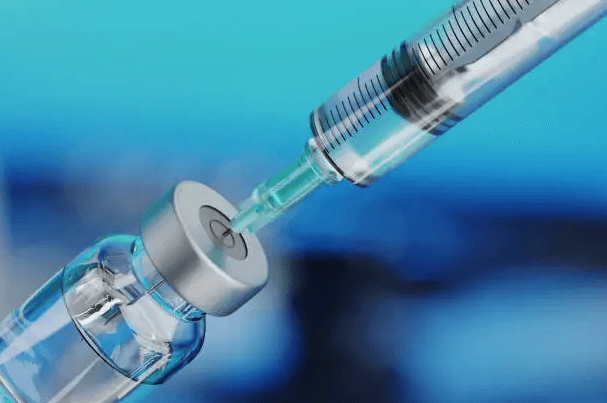 A close-up of a syringe drawing a liquid into a small vial.