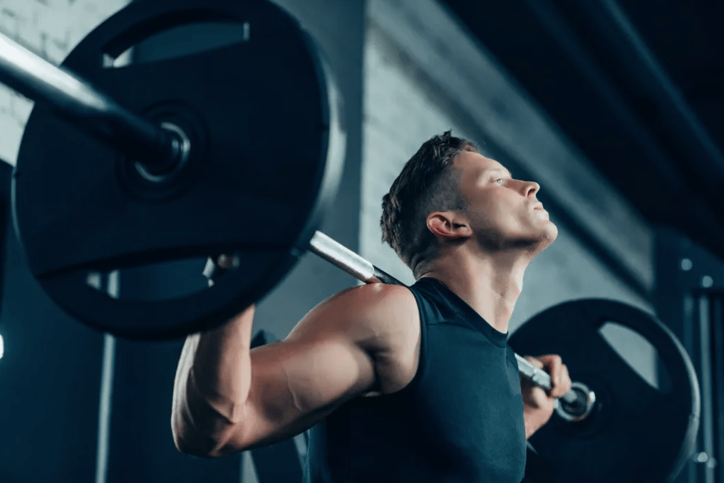 Man lifting a barbell in a gym with a focused expression