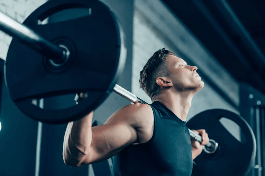 Man lifting a barbell in a gym with a focused expression