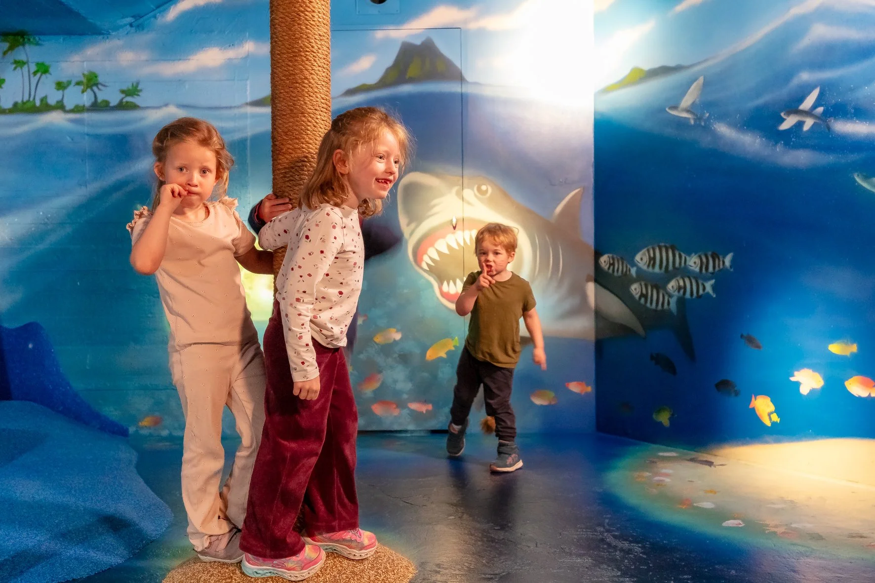 En gruppe barn i rosa og svarte vester ser på en utstilling om sjøfart, med en stor modell av et gammelt norsk vikingskip og en digital skjerm. Museet har også en modell av et moderne skipsdyp.