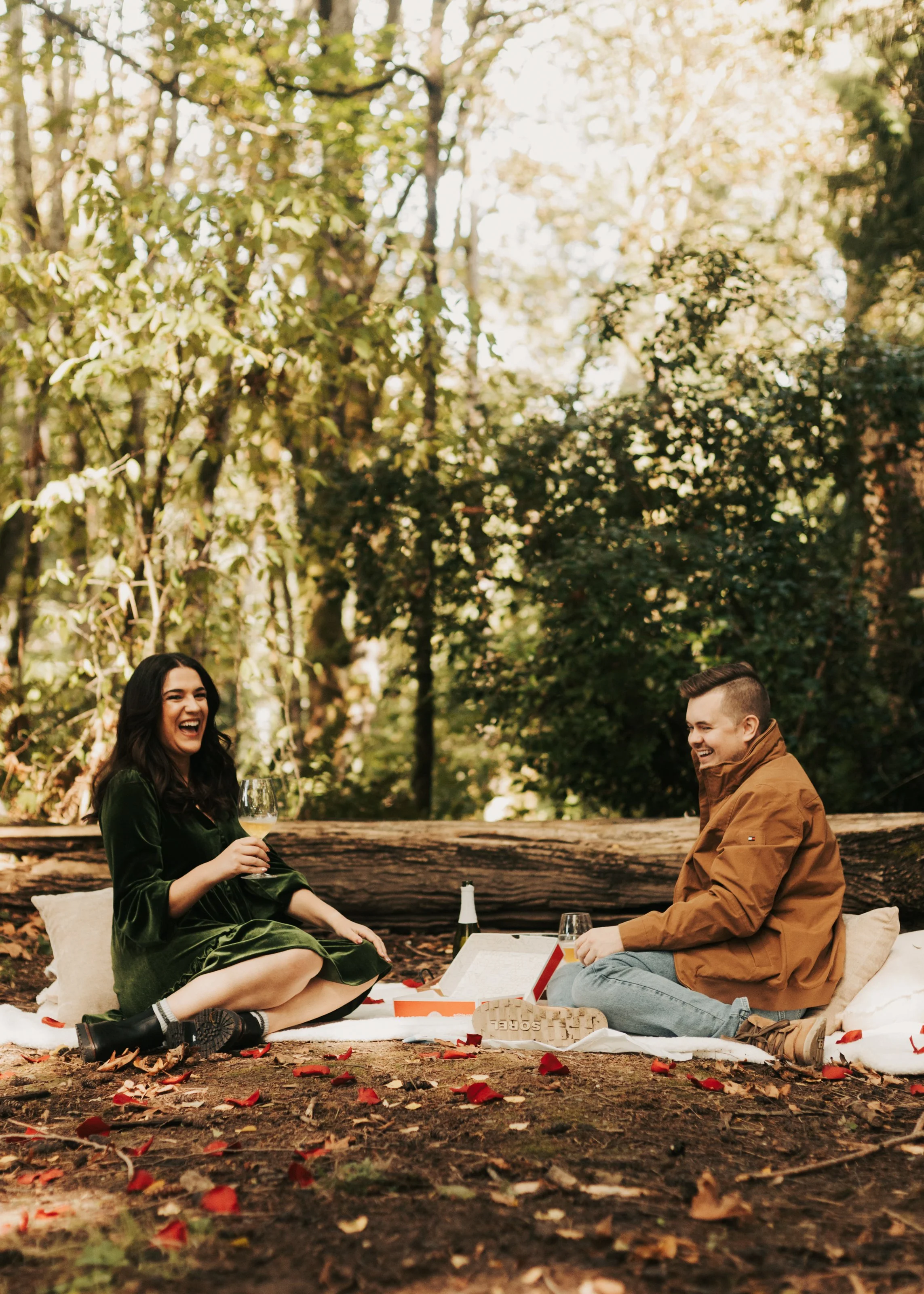 A couple sitting on a blanket having a picnic in the woods. St. Edwards State Park Washington engagement