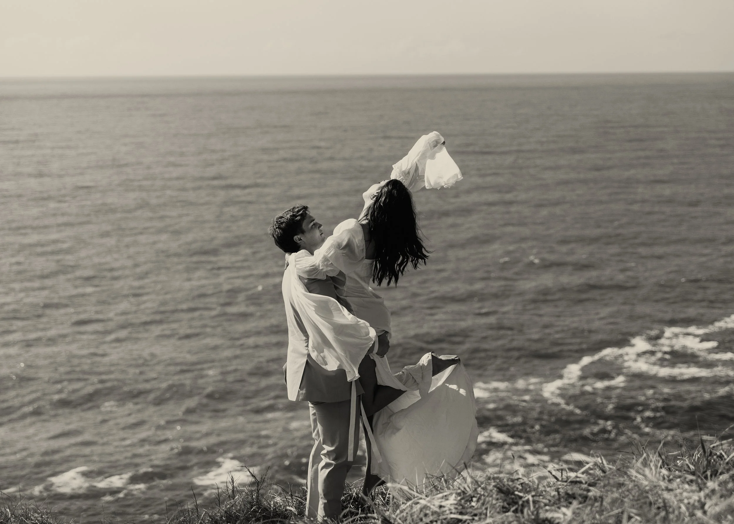 A couple standing on a grassy cliff overlooking the ocean. Elk Flats Oregon elopement