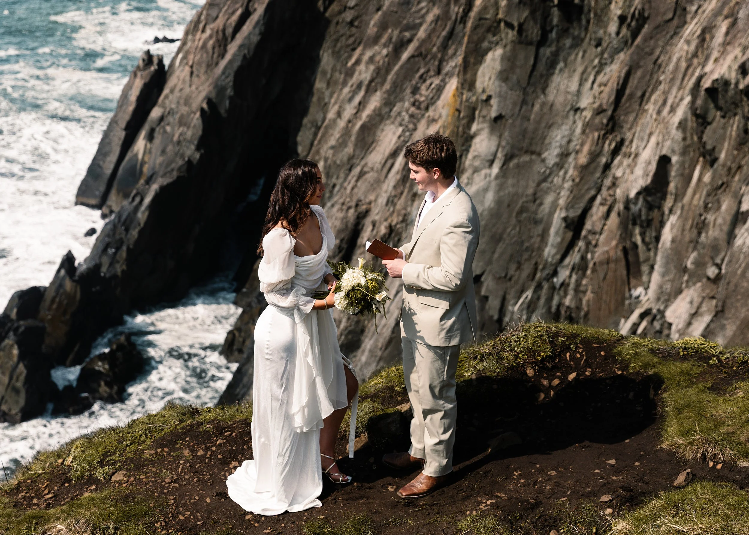 A couple getting an elopement on a rocky cliffside overlooking the ocean at Elk Flats in Oregon