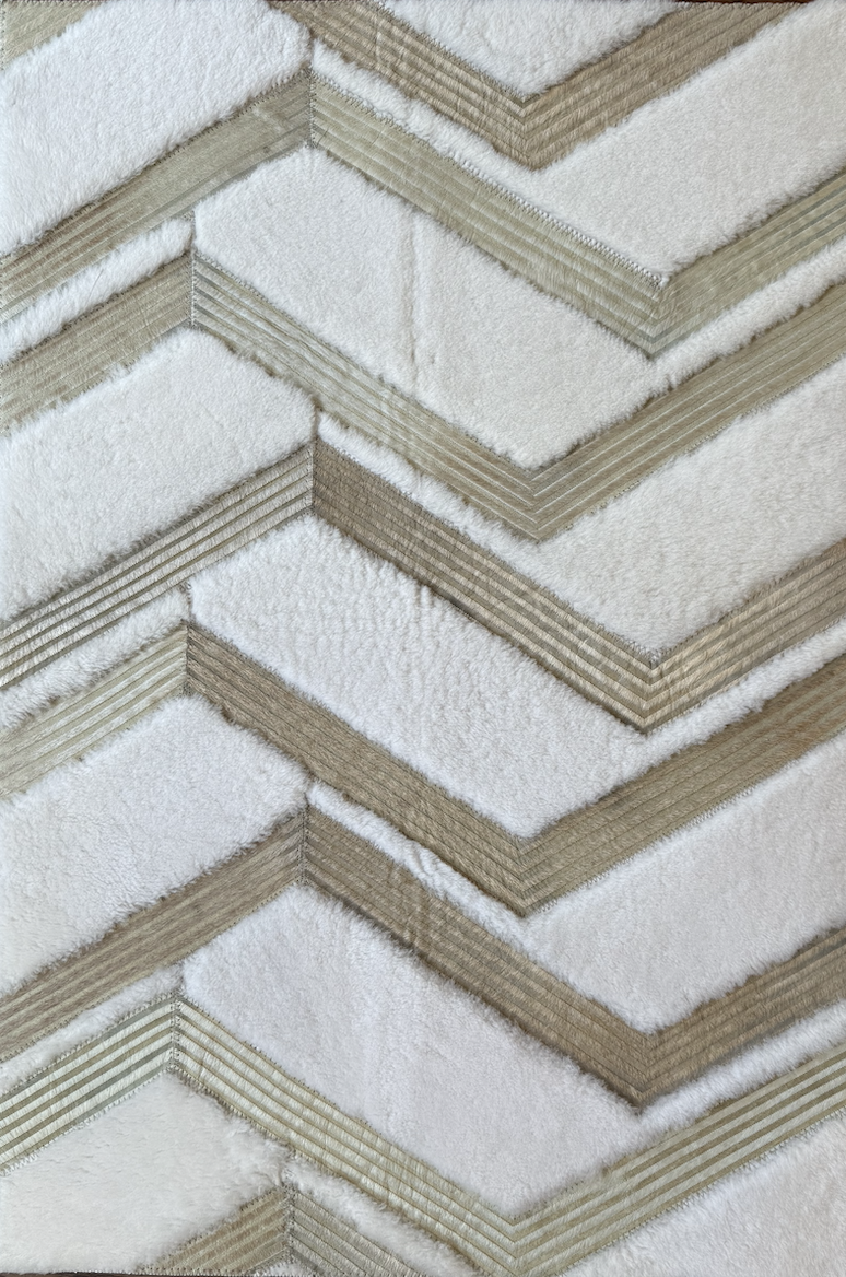 Close-up view of a layered tile or stone surface with a chevron pattern, featuring shades of beige, cream, and white.