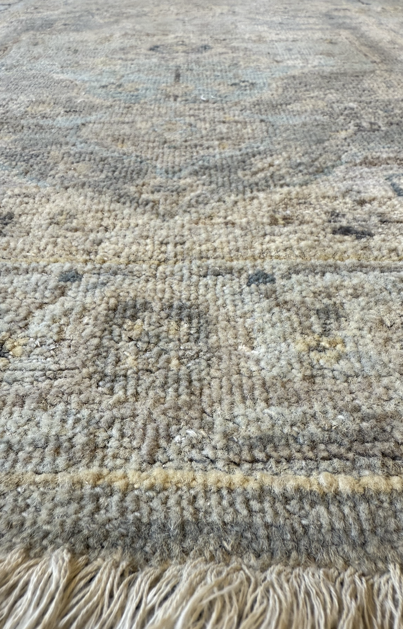 Close-up of a beige and brown patterned area rug with fringes at the edge.
