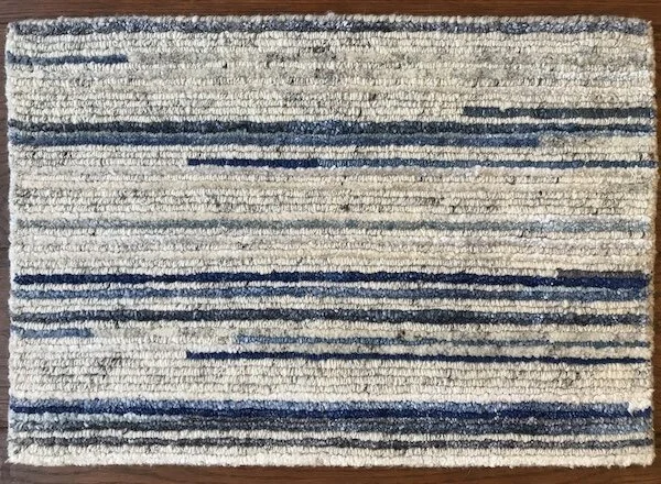 A rectangular area rug with horizontal blue and beige stripes on a wooden floor.