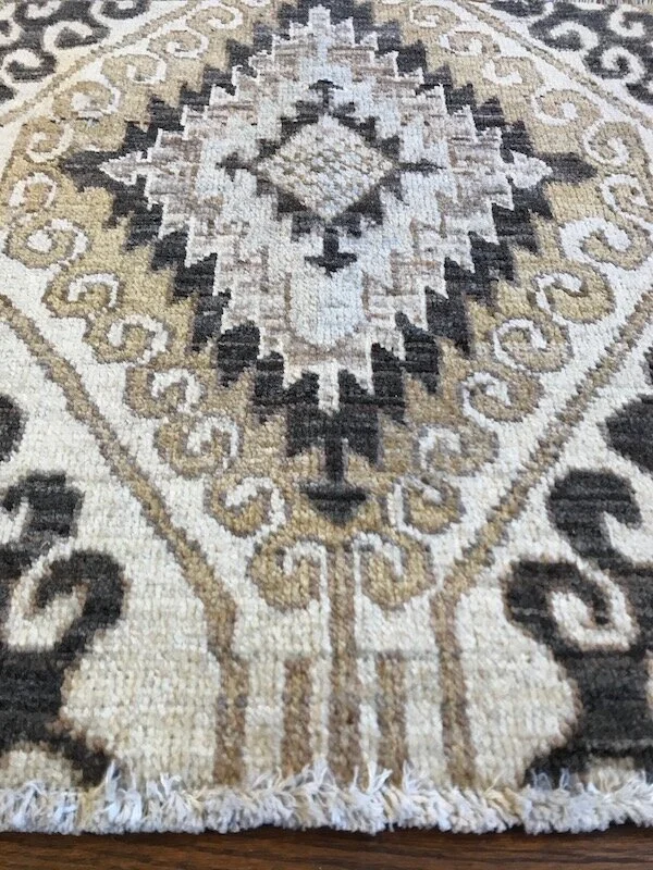 Close-up of a decorative area rug with a geometric floral pattern in beige, black, and cream colors.