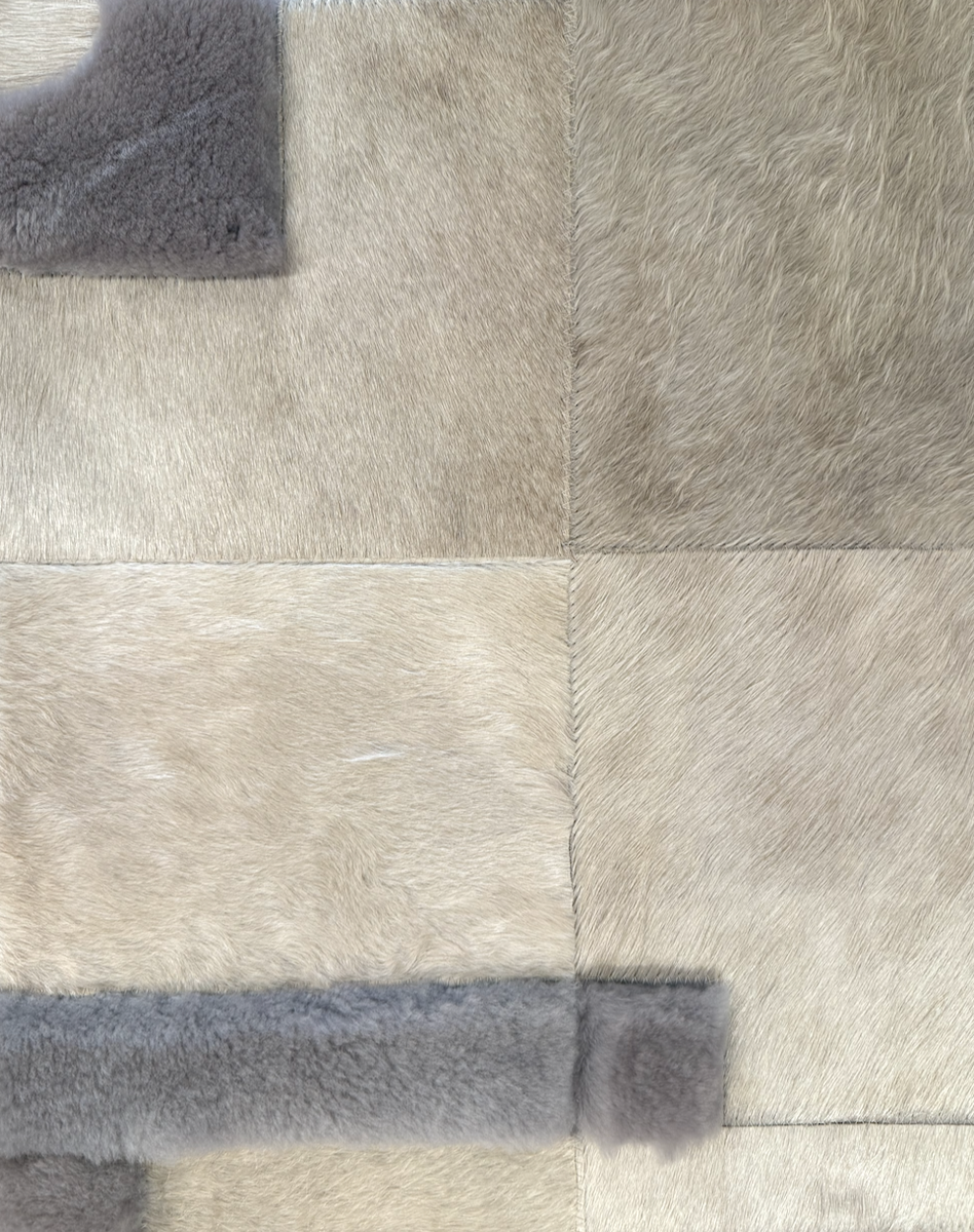 Close-up of a patchwork fur rug with beige and gray sections.