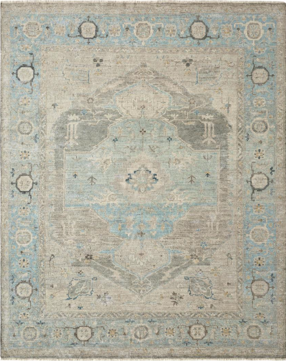 A vintage area rug with a distressed pattern in shades of beige, light blue, and gray, featuring an intricate central medallion design and a decorative border.
