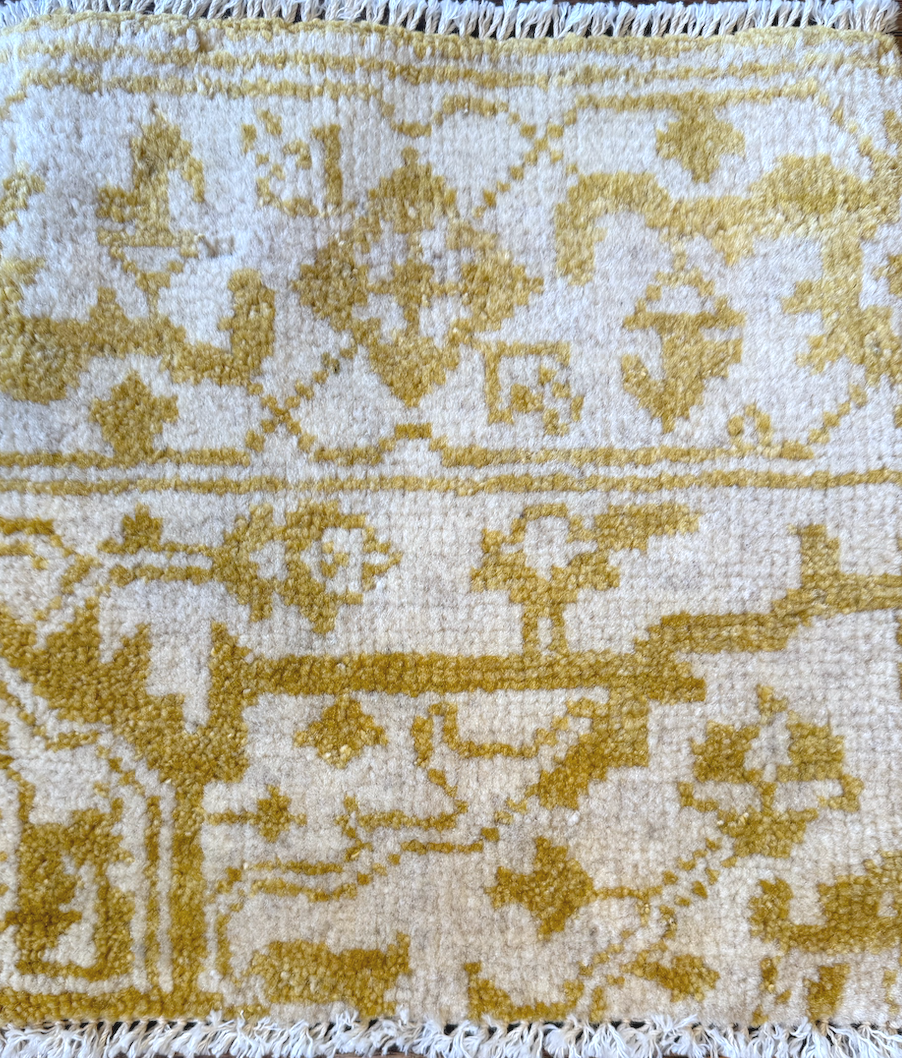Close-up of a decorative rug with a yellow and white pattern.