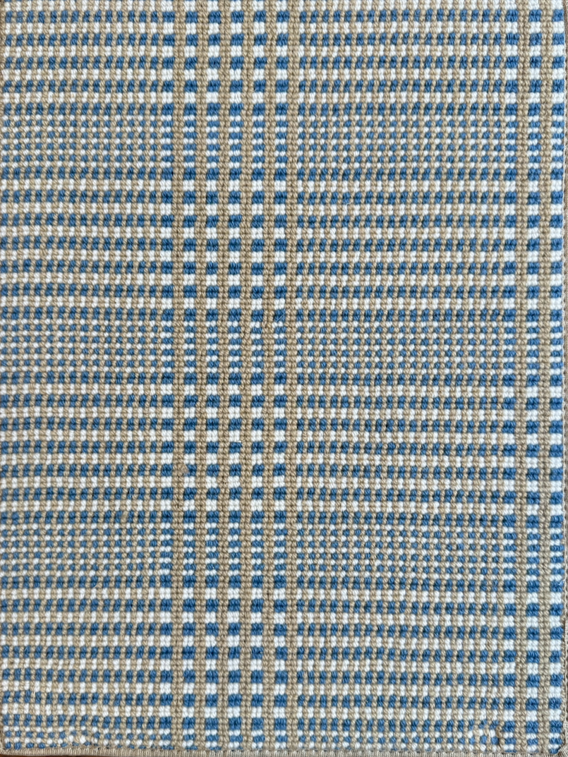Close-up view of a plaid fabric featuring a pattern of small blue, beige, and white checks.